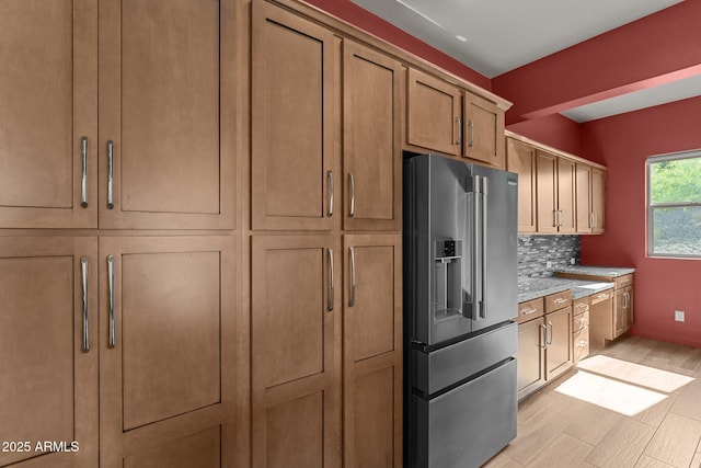 kitchen with high end fridge, brown cabinets, light countertops, light wood-style floors, and tasteful backsplash