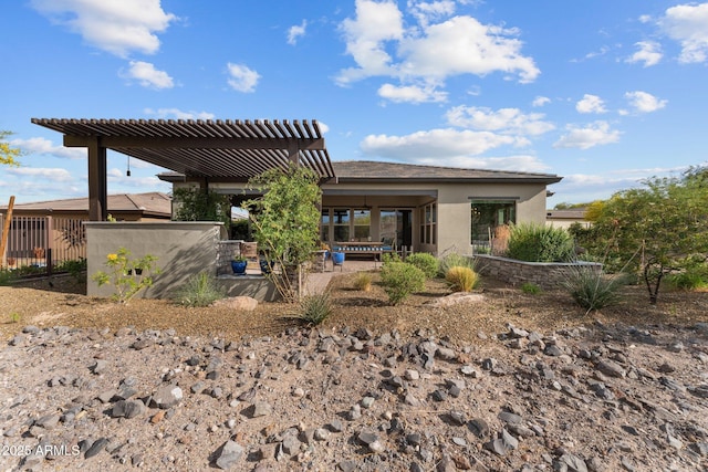 rear view of house featuring stucco siding, a pergola, and a patio area
