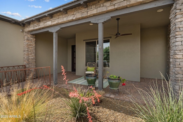 entrance to property with fence, a patio, stucco siding, and a ceiling fan
