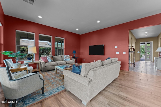 living room with recessed lighting, visible vents, and wood finished floors