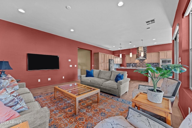 living room featuring light wood-style floors, visible vents, and recessed lighting