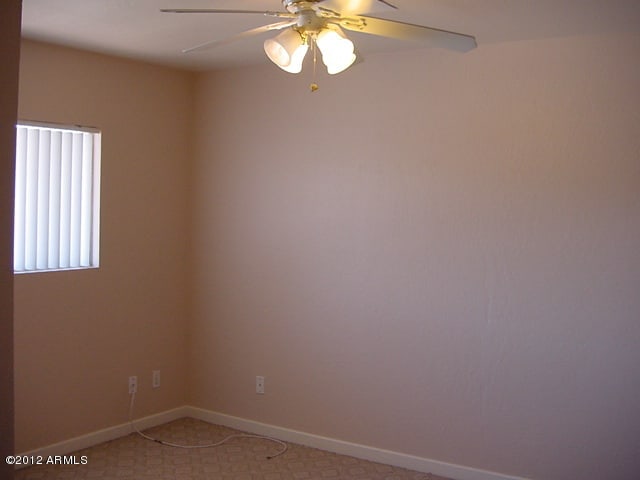 empty room with baseboards, light carpet, and a ceiling fan
