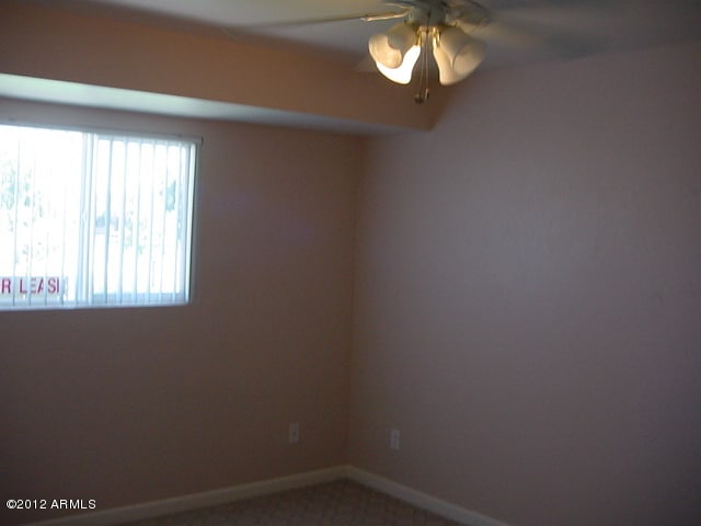 carpeted empty room with ceiling fan and baseboards