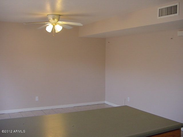 empty room with visible vents, baseboards, ceiling fan, and light tile patterned floors