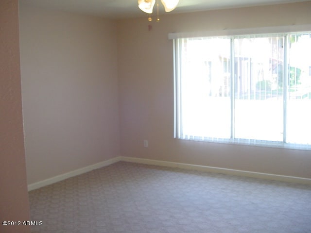 carpeted spare room with baseboards and ceiling fan