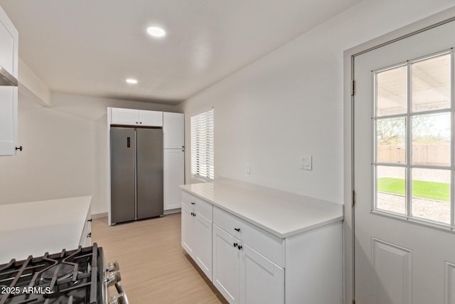 kitchen featuring light countertops, white cabinets, light wood finished floors, and freestanding refrigerator