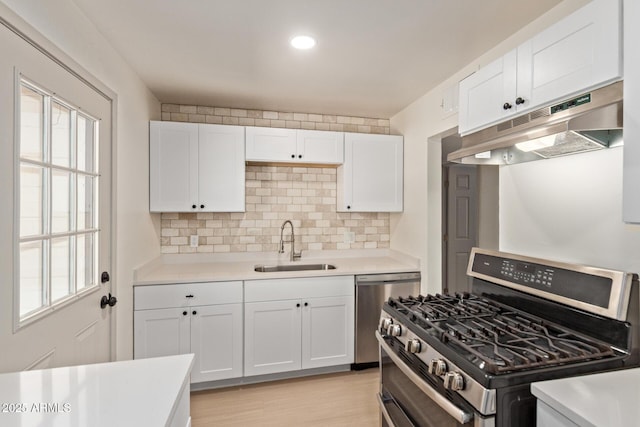 kitchen with under cabinet range hood, a sink, stainless steel range with gas cooktop, light countertops, and dishwasher