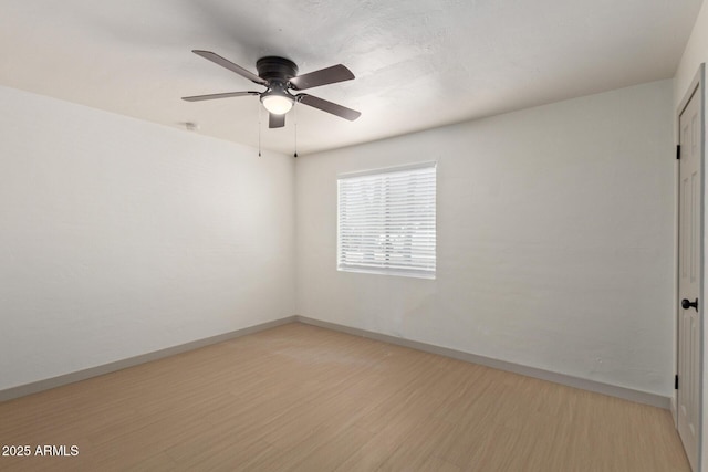 unfurnished room with ceiling fan, light wood-type flooring, and baseboards