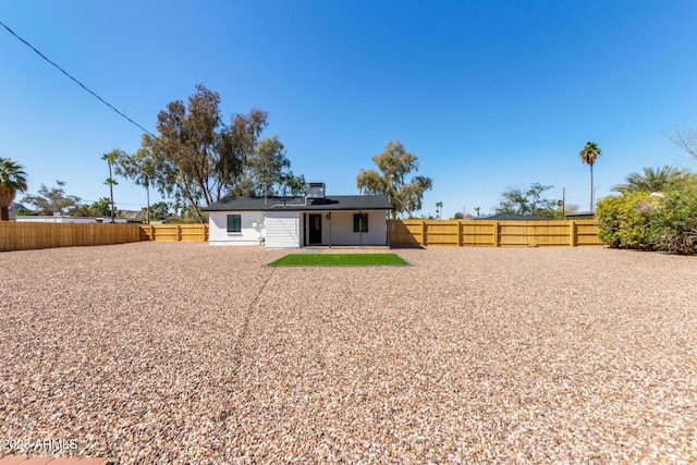 back of house featuring a fenced backyard, solar panels, and a patio