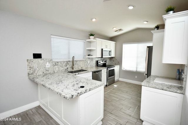 kitchen featuring backsplash, stainless steel appliances, sink, white cabinets, and lofted ceiling