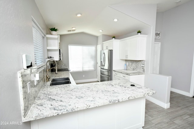 kitchen with kitchen peninsula, backsplash, sink, stainless steel fridge with ice dispenser, and white cabinetry