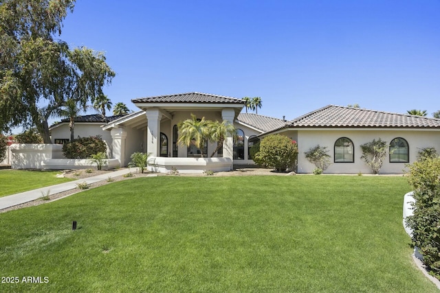 view of front of home featuring a tile roof, stucco siding, and a front lawn