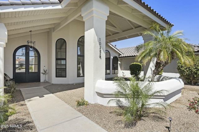 view of exterior entry with stucco siding, a tiled roof, and french doors