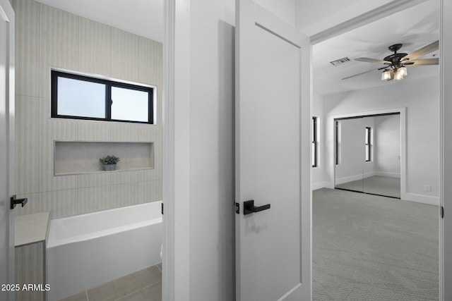 bathroom featuring a bath, ceiling fan, visible vents, and a wealth of natural light