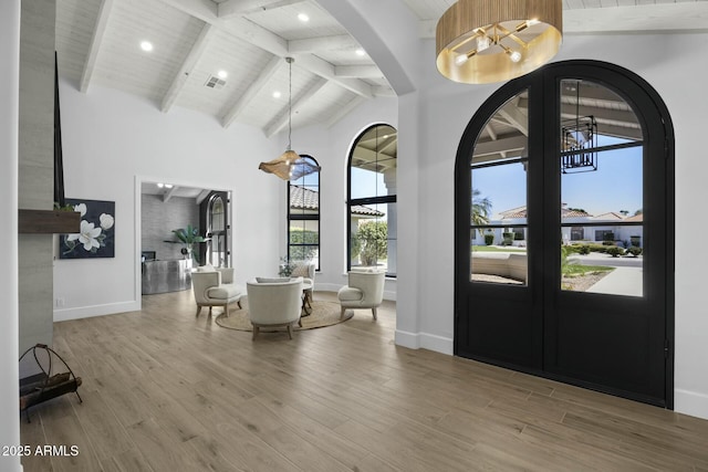 foyer entrance featuring visible vents, high vaulted ceiling, light wood-style floors, and a chandelier