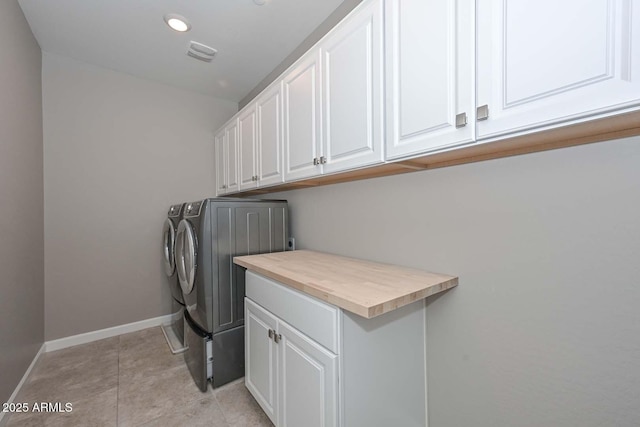 washroom featuring light tile patterned flooring, cabinets, and washer and dryer