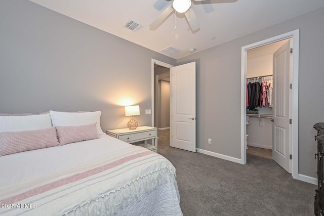 bedroom with dark colored carpet, a spacious closet, ceiling fan, and a closet