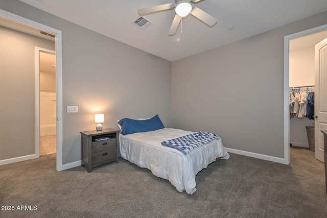 carpeted bedroom featuring a walk in closet, a closet, and ceiling fan