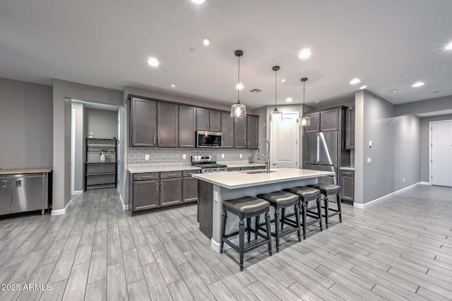 kitchen featuring sink, dark brown cabinets, hanging light fixtures, a kitchen breakfast bar, and stainless steel appliances