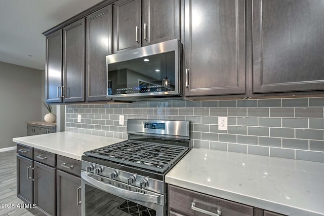 kitchen with stainless steel appliances, backsplash, dark brown cabinetry, and light hardwood / wood-style floors