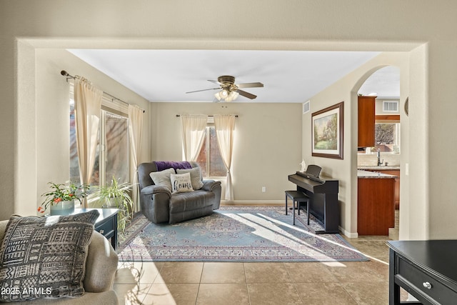 living area featuring ceiling fan, sink, and light tile patterned flooring