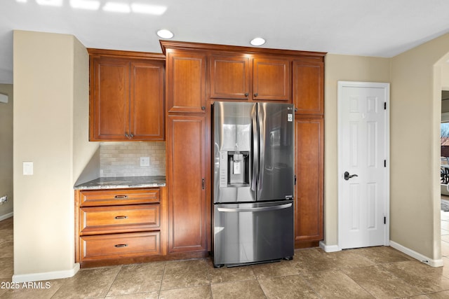 kitchen with stainless steel refrigerator with ice dispenser and tasteful backsplash