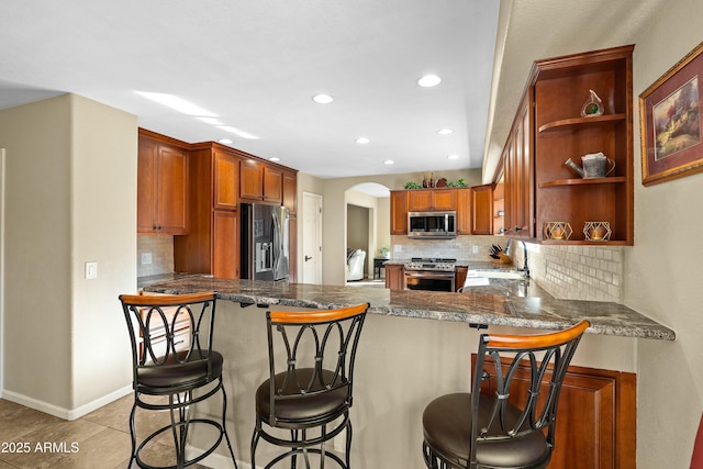 kitchen featuring a kitchen breakfast bar, stainless steel appliances, backsplash, and kitchen peninsula