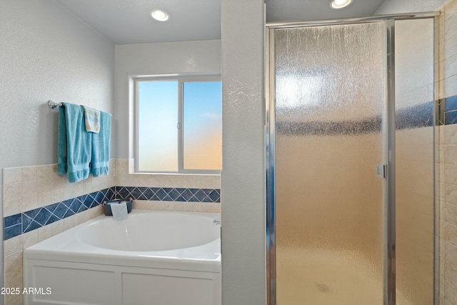 bathroom featuring tile walls and independent shower and bath