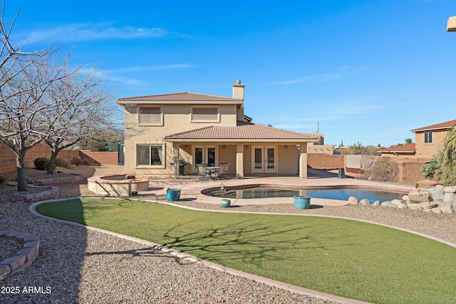 back of property with a patio area, a fire pit, a yard, french doors, and a fenced in pool