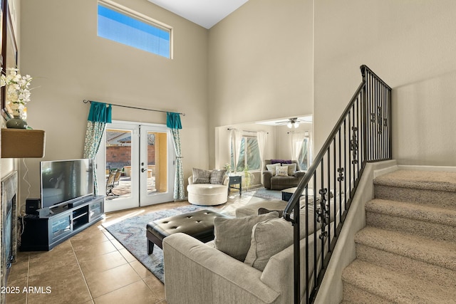 living room with ceiling fan, french doors, light tile patterned flooring, and a high ceiling