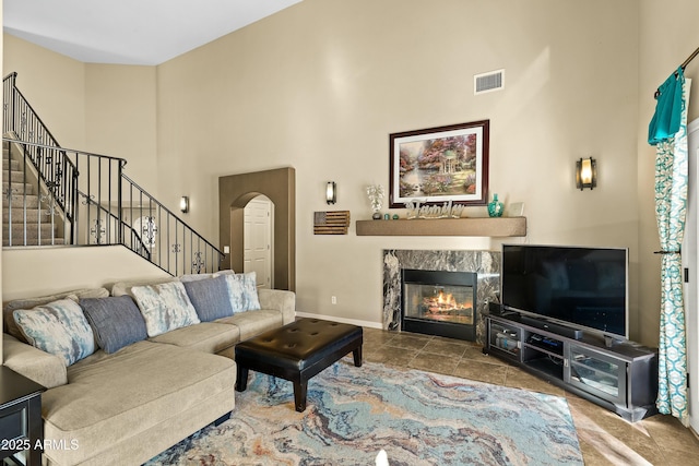 living room with a tiled fireplace and a high ceiling