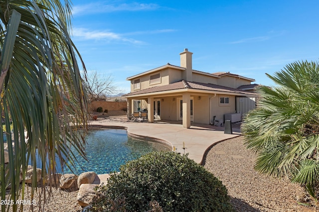 rear view of property with a fenced in pool and a patio