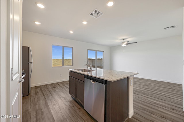 kitchen with dark brown cabinets, stainless steel appliances, a kitchen island with sink, dark wood-type flooring, and sink