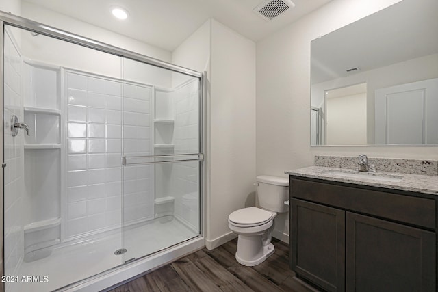 bathroom with hardwood / wood-style flooring, vanity, toilet, and an enclosed shower