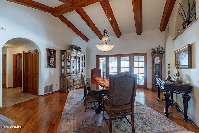 dining space with hardwood / wood-style floors, beamed ceiling, and high vaulted ceiling