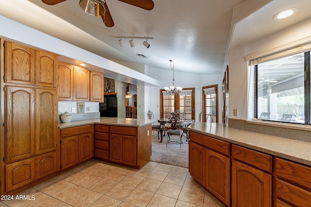 kitchen with pendant lighting, lofted ceiling, kitchen peninsula, and light tile patterned floors