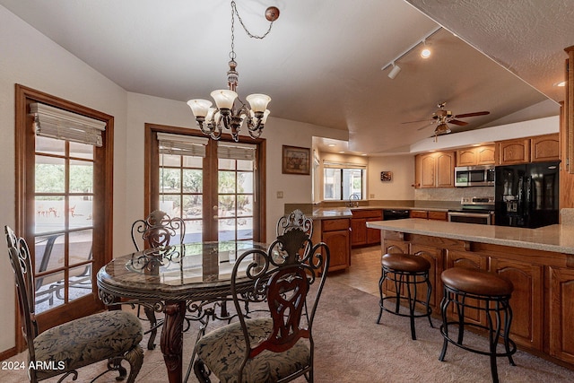 tiled dining area featuring french doors, ceiling fan with notable chandelier, sink, vaulted ceiling, and a textured ceiling