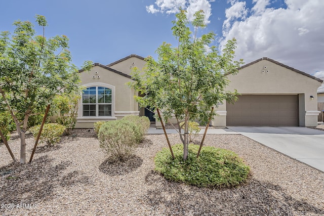 view of front facade featuring an attached garage, a tile roof, concrete driveway, and stucco siding