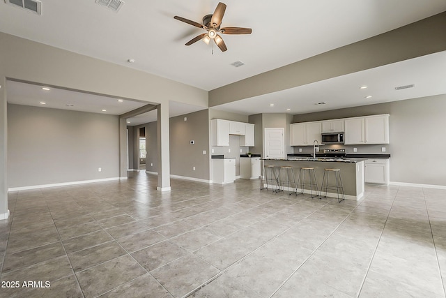 living area featuring baseboards, a ceiling fan, and visible vents