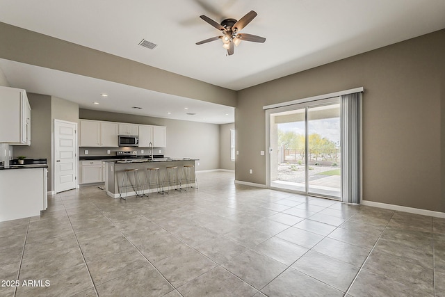 living area featuring light tile patterned flooring, ceiling fan, baseboards, visible vents, and recessed lighting