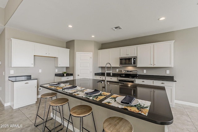 kitchen with dark countertops, visible vents, a sink, baseboards, and appliances with stainless steel finishes