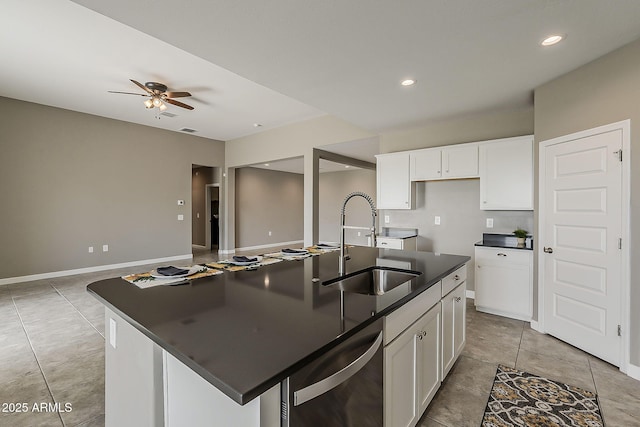 kitchen with dark countertops, dishwasher, white cabinetry, a sink, and ceiling fan