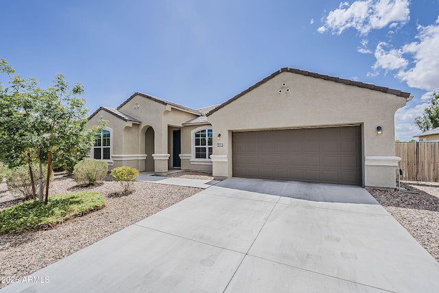 view of front of house with a tiled roof, concrete driveway, fence, a garage, and stucco siding