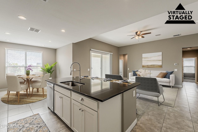 kitchen with dark countertops, dishwasher, visible vents, a healthy amount of sunlight, and a sink