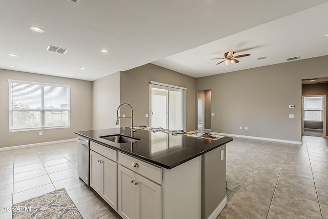 kitchen with a sink, dark countertops, visible vents, dishwasher, and light tile patterned floors