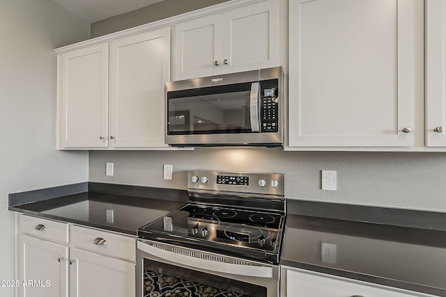 kitchen featuring dark countertops, appliances with stainless steel finishes, and white cabinetry