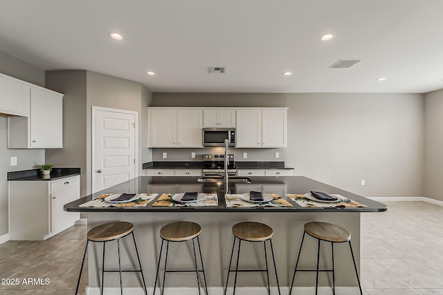 kitchen featuring dark countertops, visible vents, a sink, and stainless steel microwave