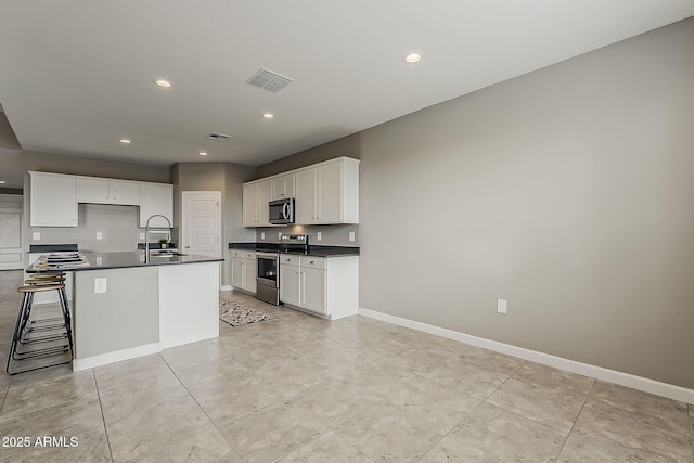 kitchen featuring recessed lighting, dark countertops, visible vents, a sink, and appliances with stainless steel finishes