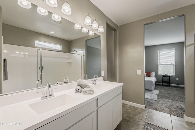 ensuite bathroom with a shower stall, baseboards, and a sink