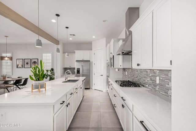 kitchen with white cabinetry, sink, stainless steel appliances, hanging light fixtures, and a spacious island